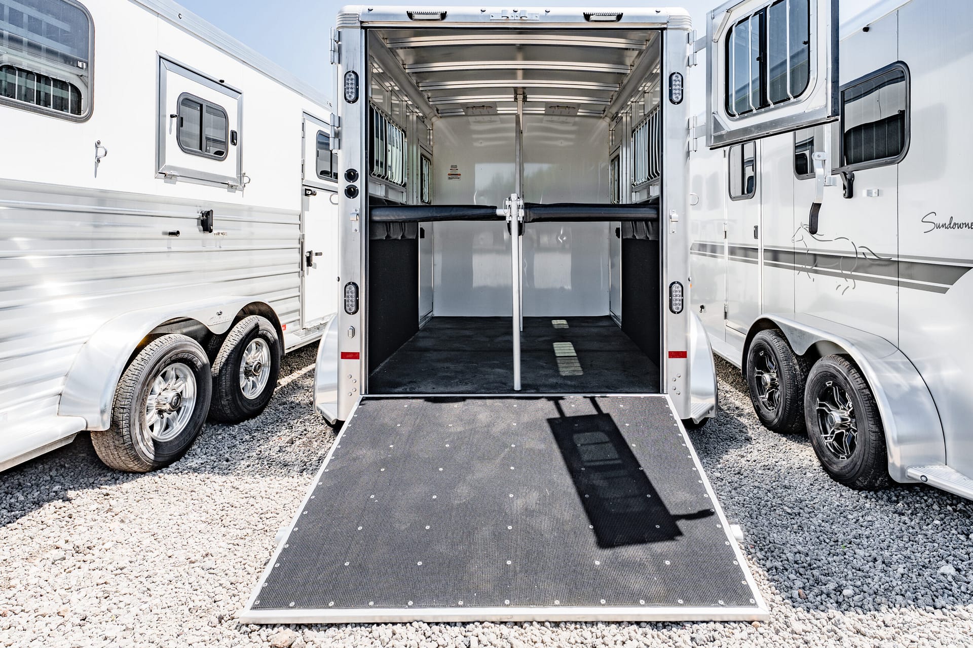 Open horse trailer with a lowered ramp, showing empty stalls and metal divider inside