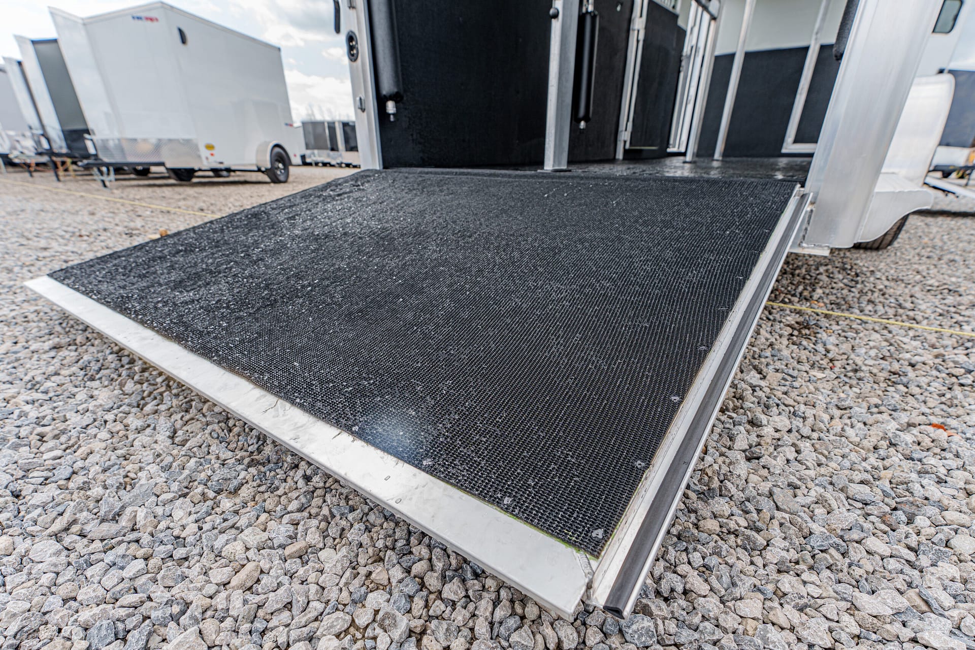 Open trailer ramp extended onto rocky ground, ready for loading or unloading gear.