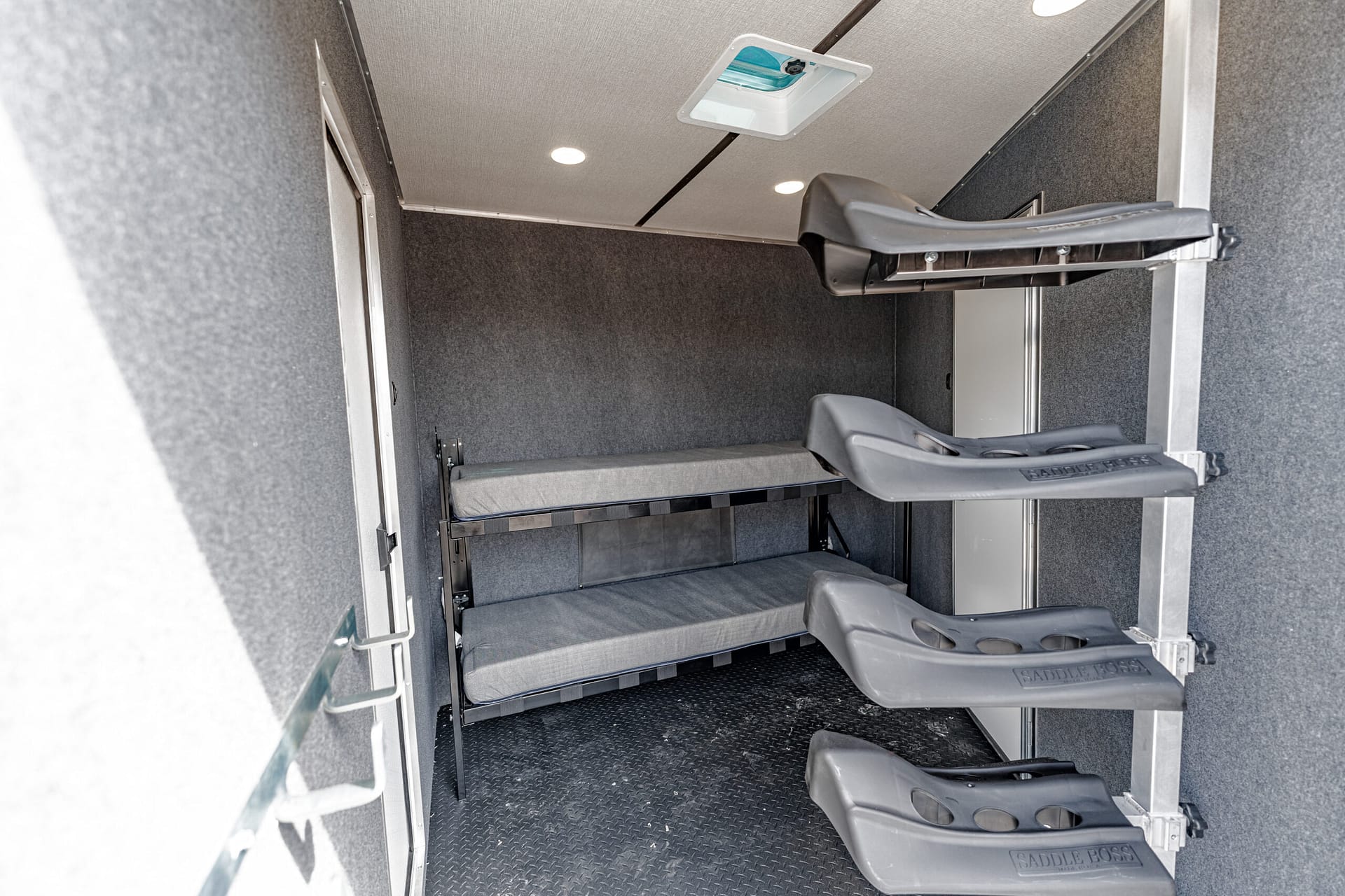 Interior of a horse trailer showing three fold-out gray steps with a padded landing and Saddle Boss branding, leading to a raised area inside the trailer.