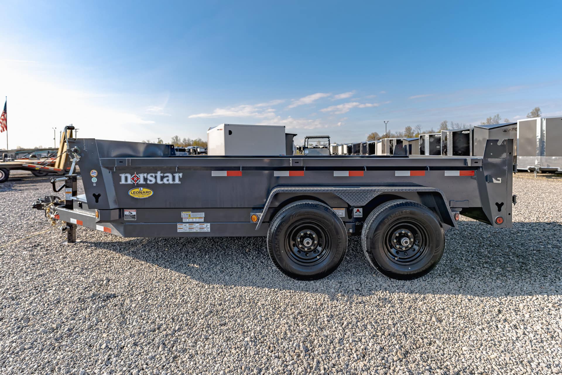 Grey Norstar trailer on a gravel lot with other trailers and a clear blue sky in the background