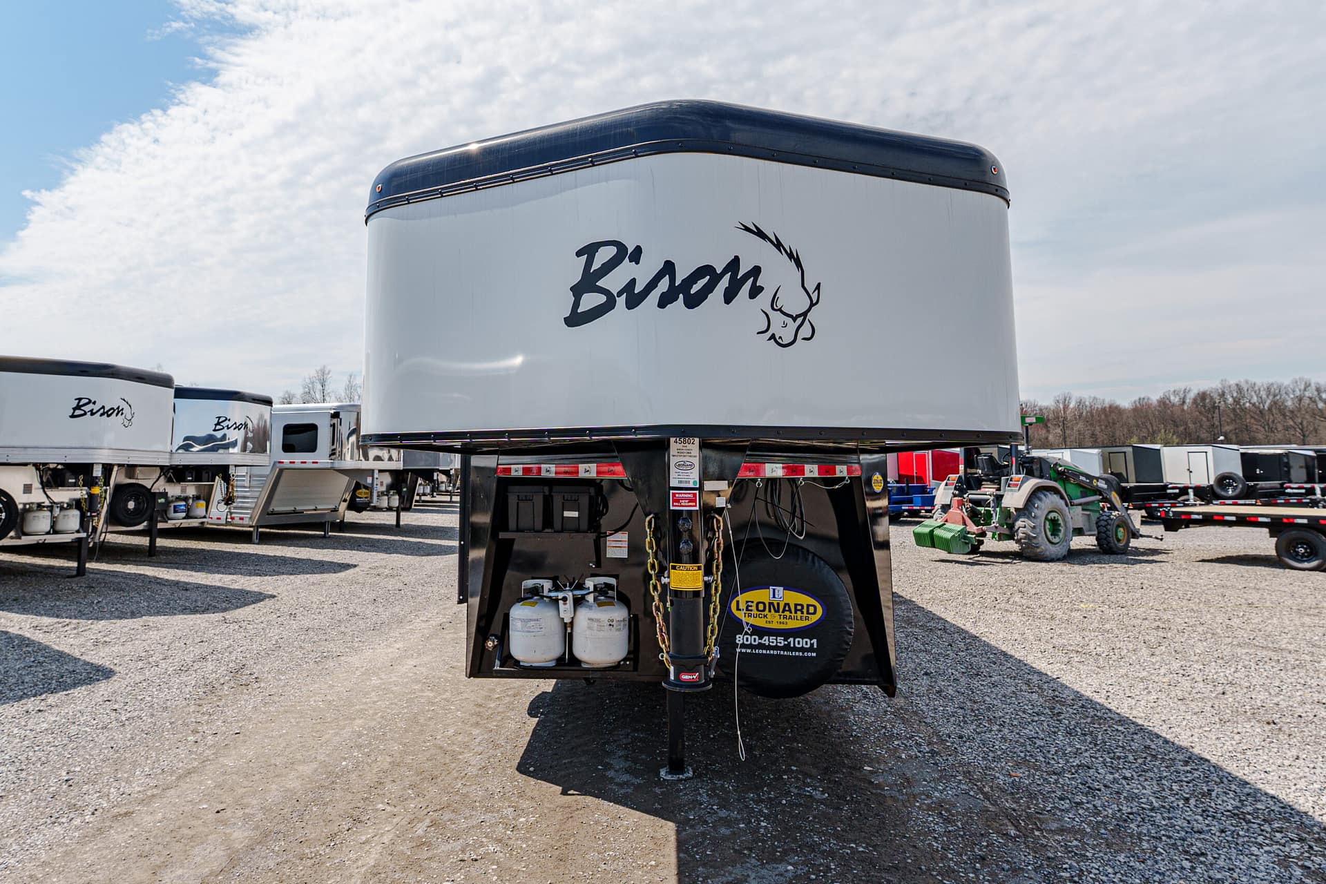 Large white Bison travel trailer front in a lot of trailers, with propane tanks and hitch at the front.