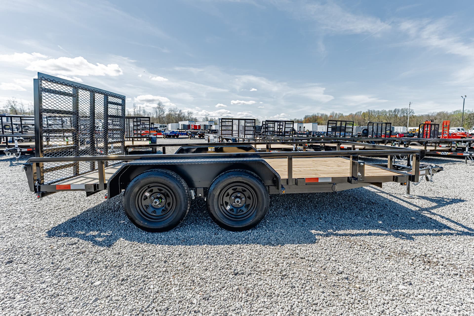 Row of flatbed trailers in a gravel lot under a clear blue sky at a trailer yard festival of equipment?