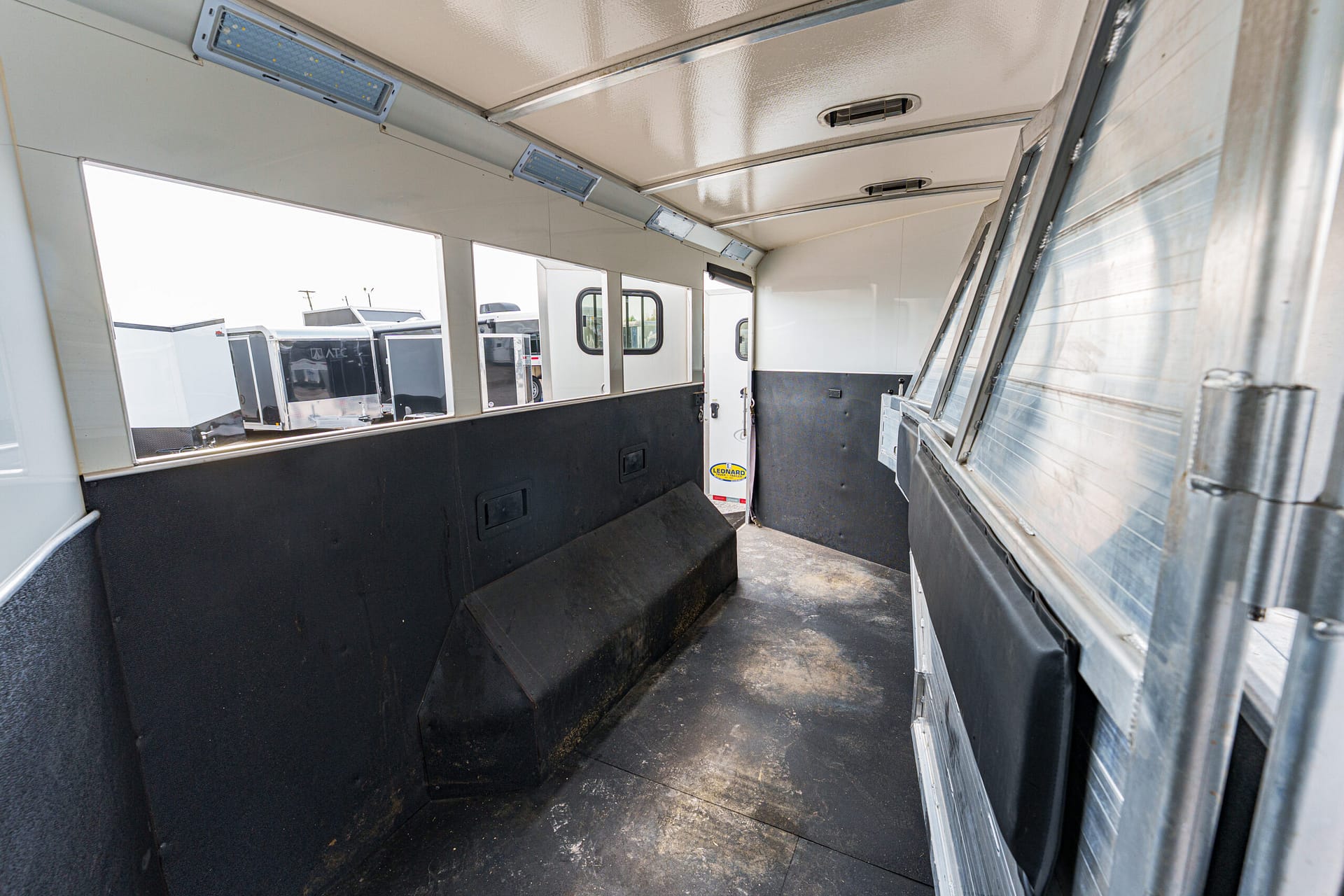 Interior of a white concession trailer with black lower walls, a narrow aisle, and windows along the left side