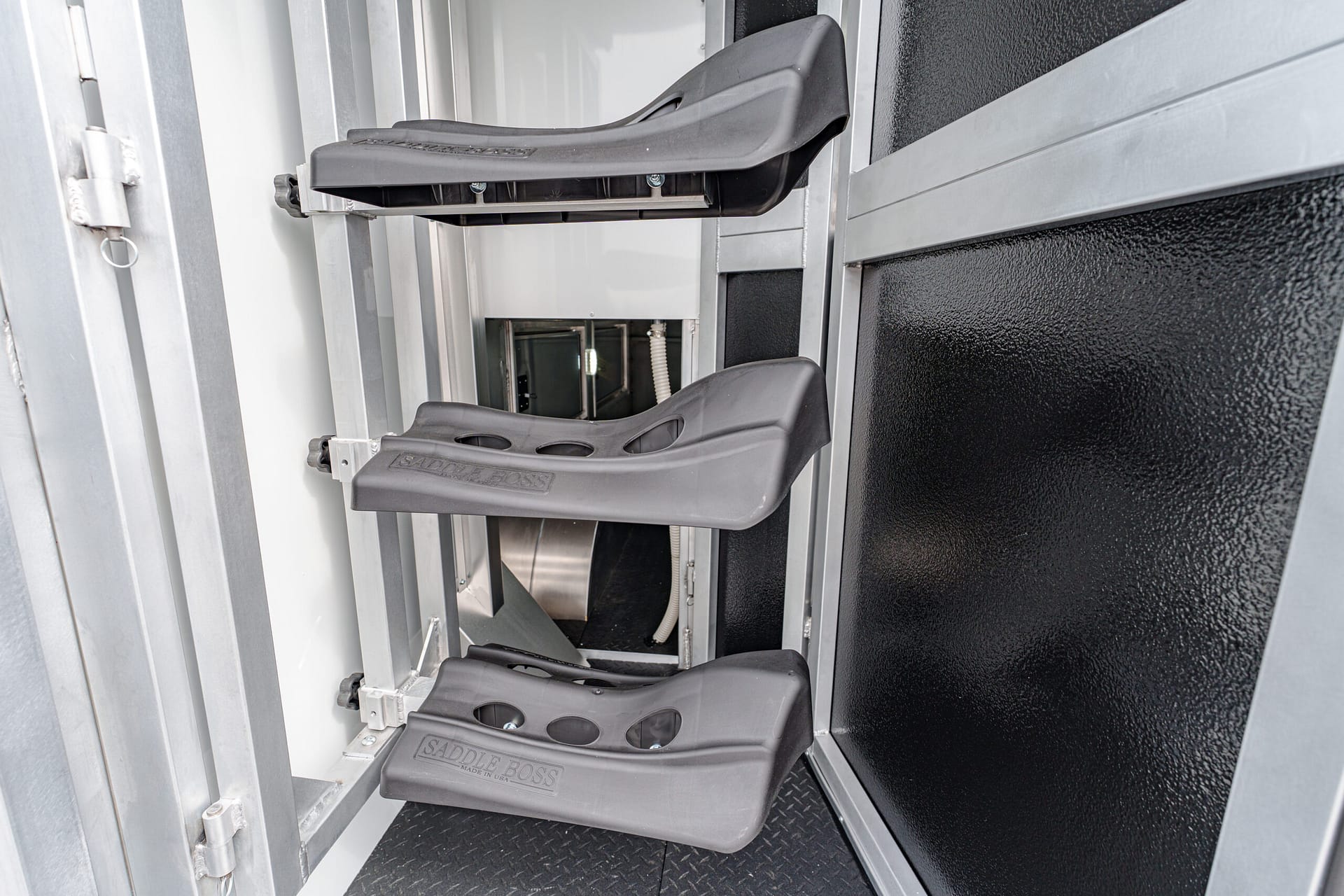 Close-up of grey plastic stair treads labeled 'SADDLE BOSS' mounted on a metallic frame inside a narrow industrial enclosure or cabinet.
