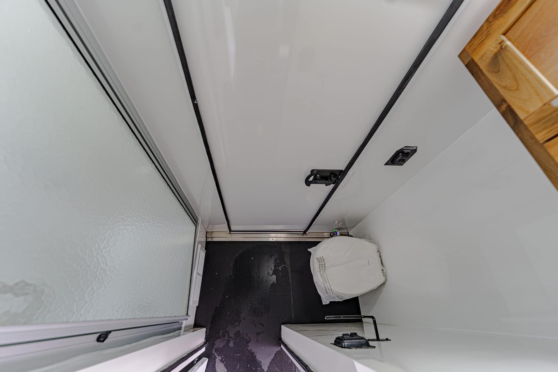 Elevator interior with closed gray doors, white walls, and a white sack on the dark floor mat.