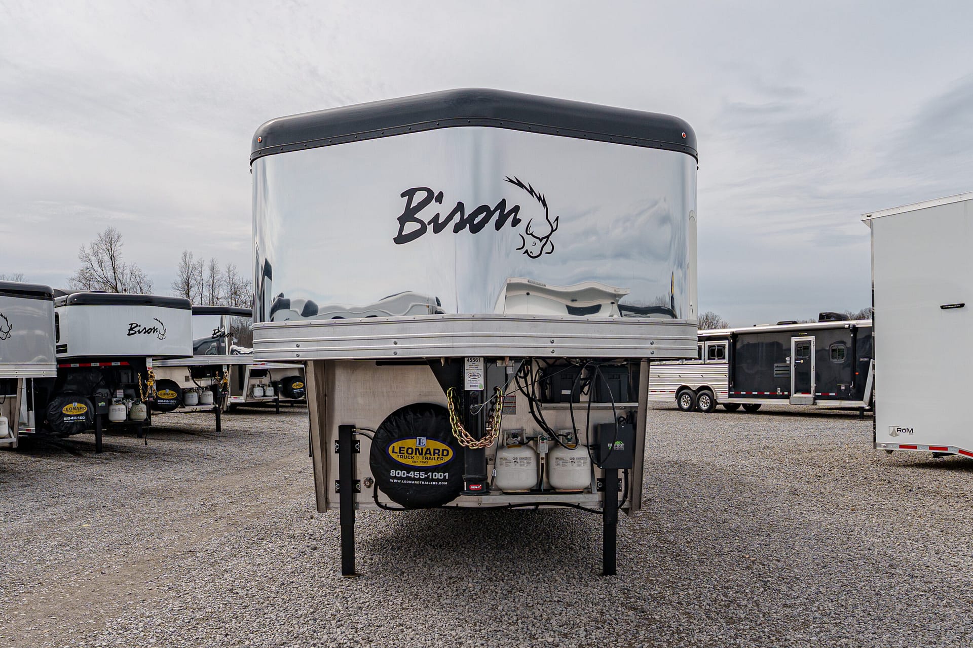 Front view of a polished silver Bison trailer parked in a lot with other trailers visible in the background.
