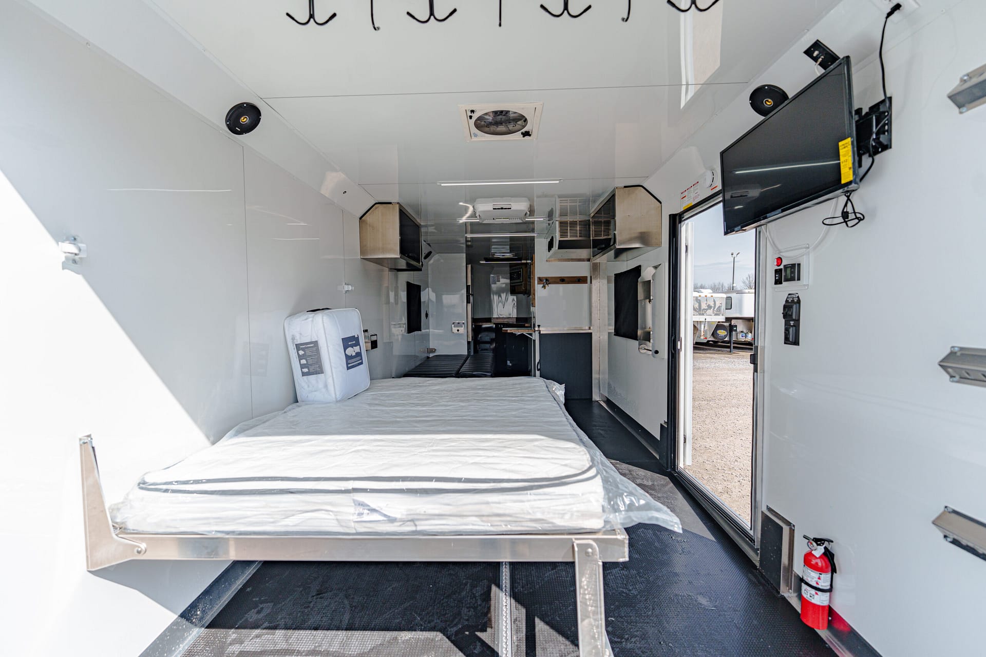 Interior of an ambulance with a long stretcher along the left wall, white cabinetry, and medical equipment; rear doorway open to outdoors