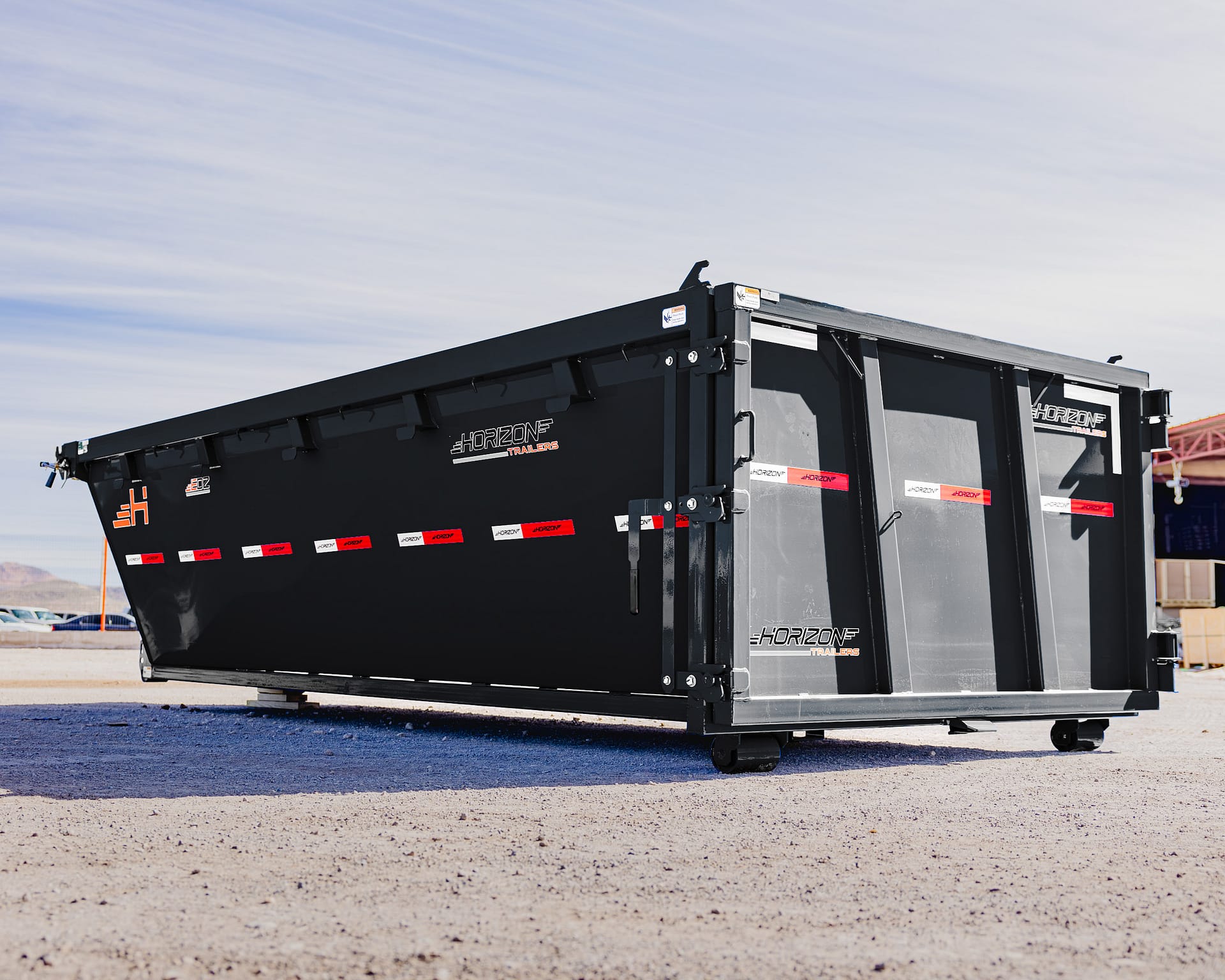 Large black Horizon trailer container on a gravel lot under a clear blue sky, rear and side visible with branding stickers.
