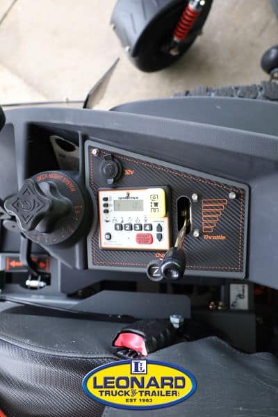 Close-up of a scooter dashboard showing the ignition knob, throttle lever, and a small control panel with the Leonard Truck & Trailer badge visible at the bottom.