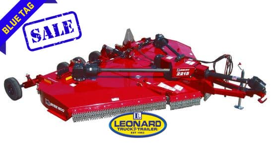 Red heavy-duty rotary mower attachment for a tractor on display, with a blue “Blue Tag SALE” banner and a Leonard Truck & Trailer logo nearby.