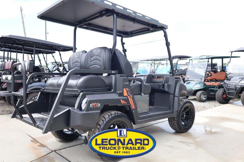 Black off-road utility vehicle (UTV) with canopy and cargo bed, four wheels, parked at a dealership lot with Leonard Truck & Trailer logo in the foreground.