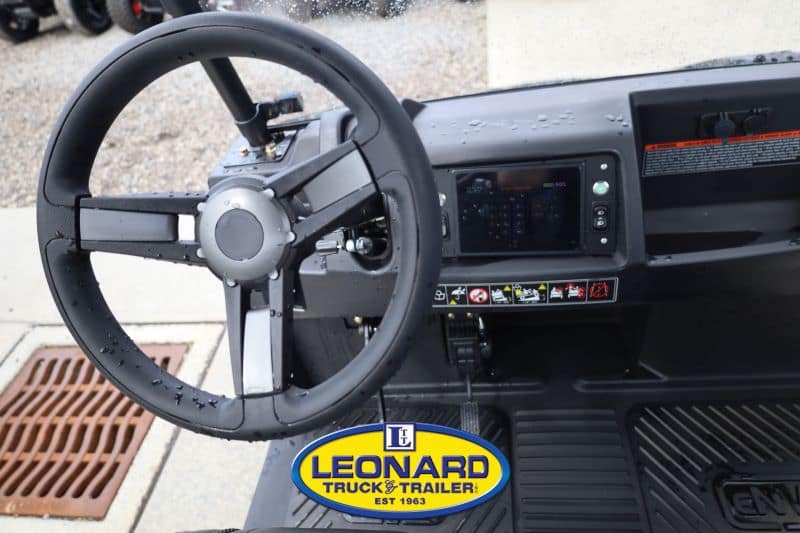 Steering wheel and dashboard of a utility truck cab, with a Leonard Truck & Trailer logo on the floor mat.