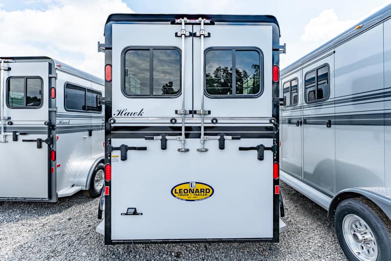 Rear view of a gray horse trailer with two back doors, small windows, and a Leonard trailer logo on the lower panel.