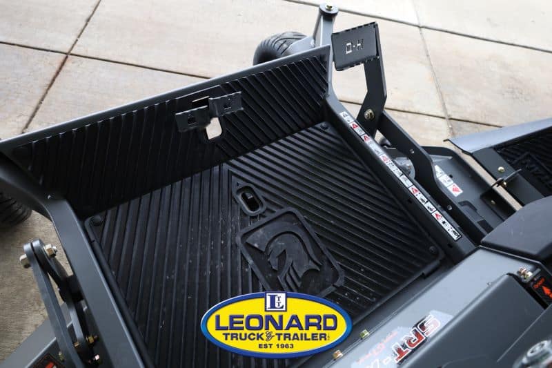 Close-up of a black trailer bed with ramp supports and a Leonard Truck & Trailer logo on the bed surface.