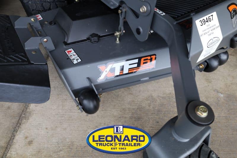 Close-up view of a heavy trailer hitch with XTF61 branding and a Leonard Truck & Trailer sticker visible on the ground signage.