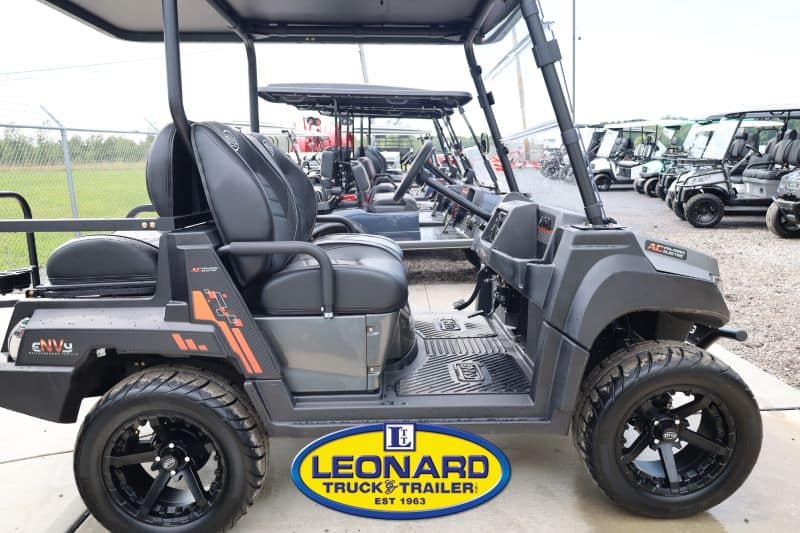 Gray utility golf cart with two front seats on display at Leonard Truck & Trailer, with other carts visible in the background.