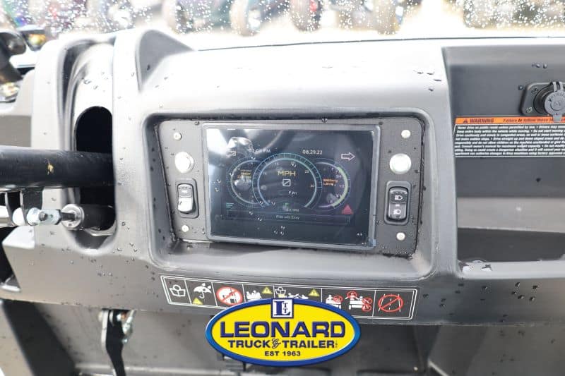 Truck dashboard with a digital gauge cluster on a built‑in touchscreen and a Leonard Truck & Trailer badge below.