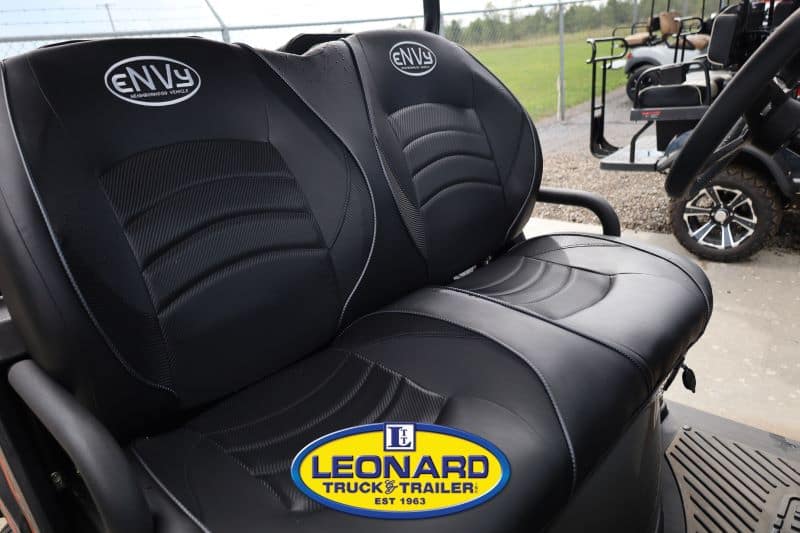 Two black leather seats with ENVy logos inside a utility vehicle; Leonard Truck & Trailer badge visible in the foreground.