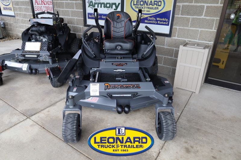 Front view of a Spartan zero-turn lawn mower on display outside Leonard Truck & Trailer, with the Leonard logo on the ground in front.